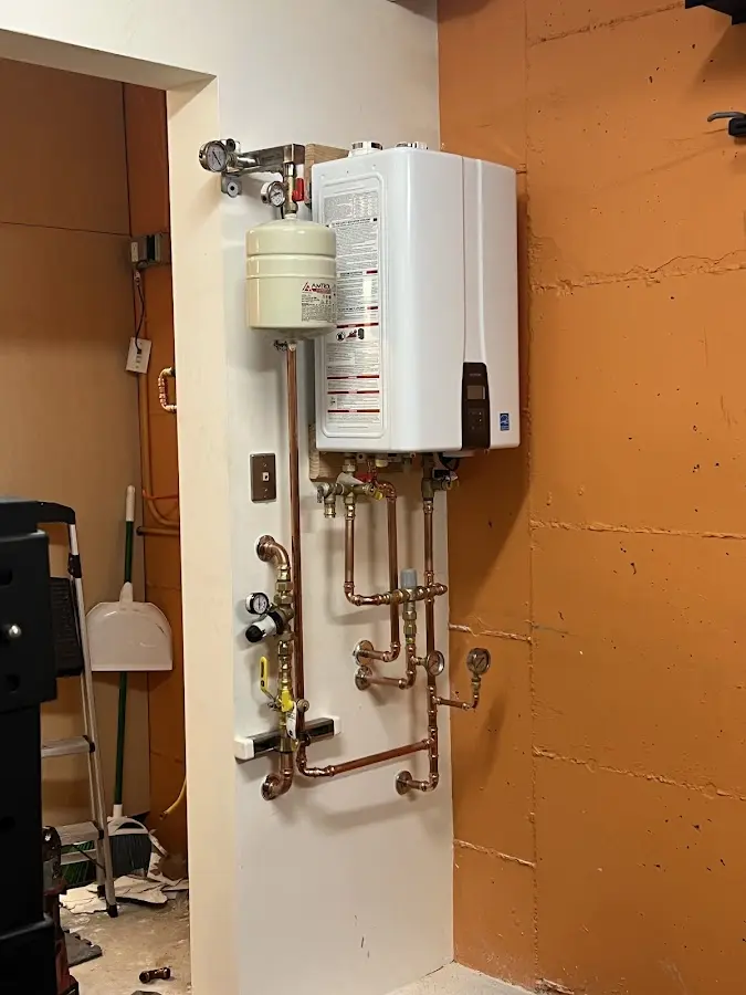 Plumbing technician inspecting water heater connections in Baldwin